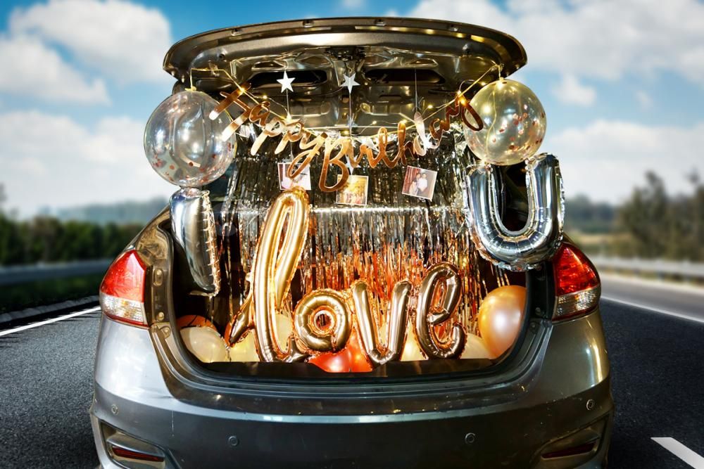 Car trunk decorated with fairy lights, balloons and flower arrangements for a midnight birthday surprise